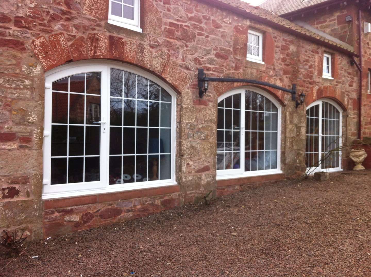 White arched windows and glazed doors in a red stone building.