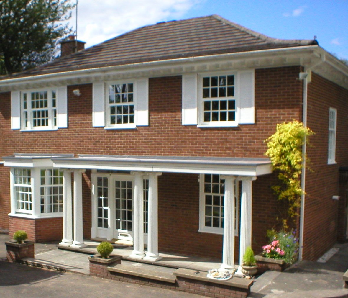 White windows across the front of a two-storey brick house.